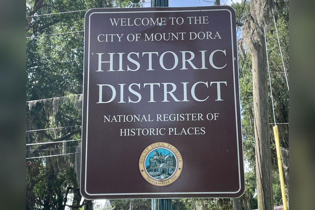 Welcome to the City of Mount Dora Historic District sign, National Register of Historic Places, on a tree-lined street