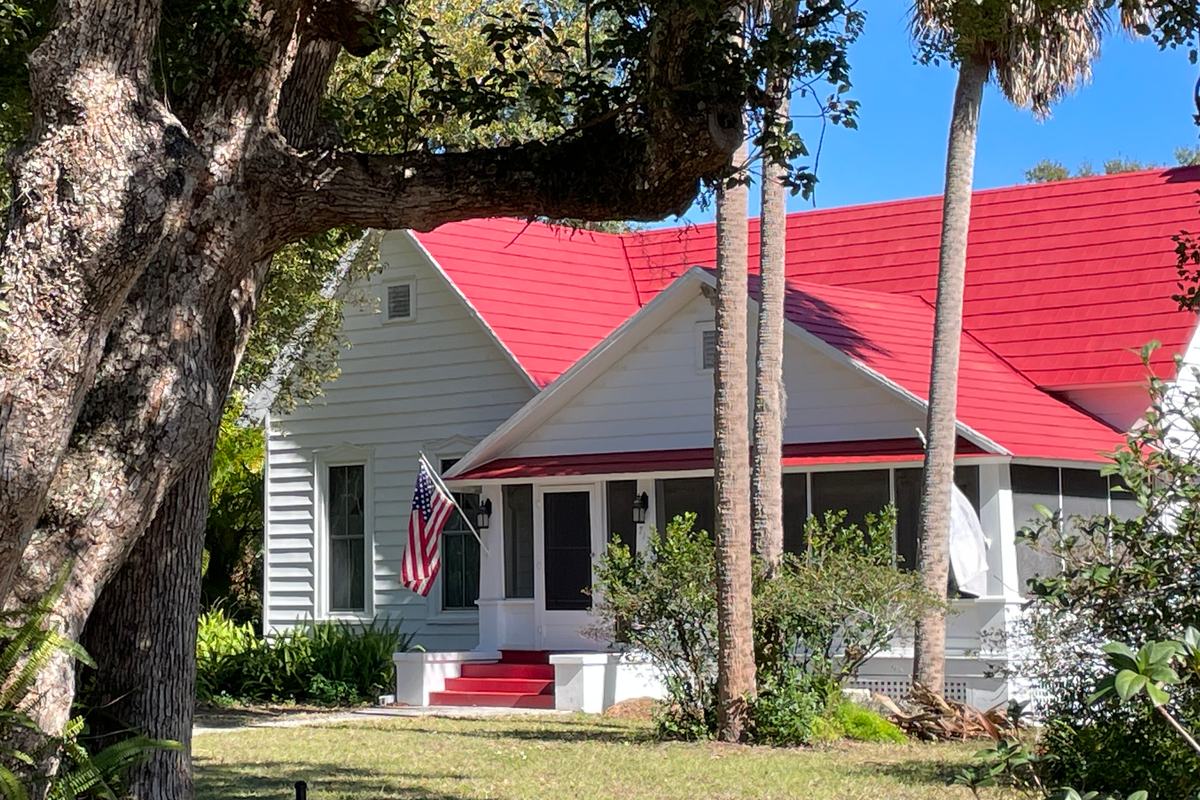Red metal roof on an older Florida home Red metal roof on a white older cottage with a screened porch under a live oak in Mount Dora, the kind of roof a 4-point inspection in Florida looks at closely